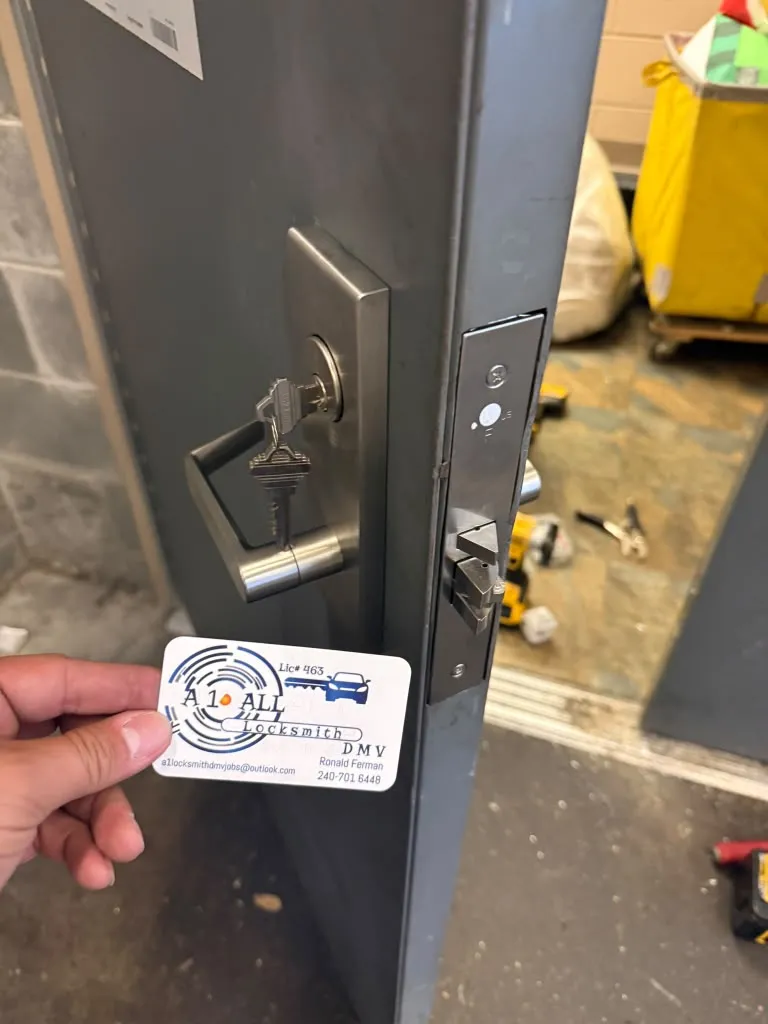 Metal door with a lever handle, keyed lock and visible latch beside an A1 All Locksmith DMV business card